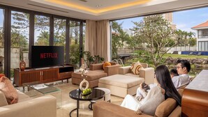 Een moderne woonkamer met een grote televisie, comfortabele zitmogelijkheden en uitzicht op de omgeving.