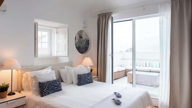 Une chambre d’hôtel avec un lit, des lampes de chevet, une fenêtre et une vue sur le balcon.