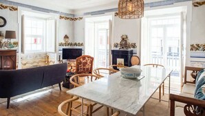 Un coin repas avec une table en marbre, des chaises en osier et un luminaire suspendu.