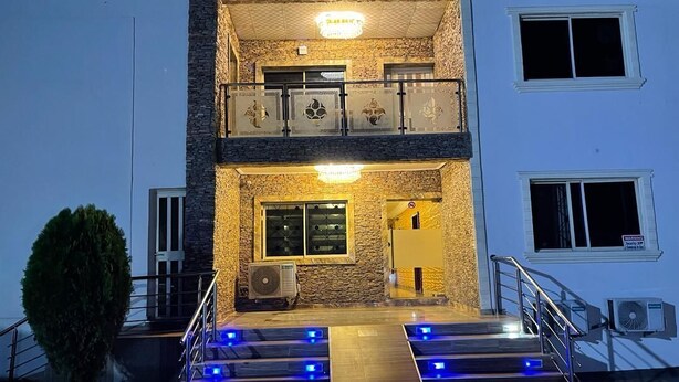 Un bâtiment à deux étages doté d’un balcon, d’un escalier éclairé de lumières bleues et d’un appareil de climatisation.