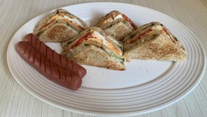 Une assiette avec un sandwich grillé et une saucisse.