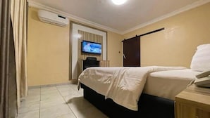 Une chambre d’hôtel équipée d’un lit, d’une télévision, d’un climatiseur et d’une armoire en bois.