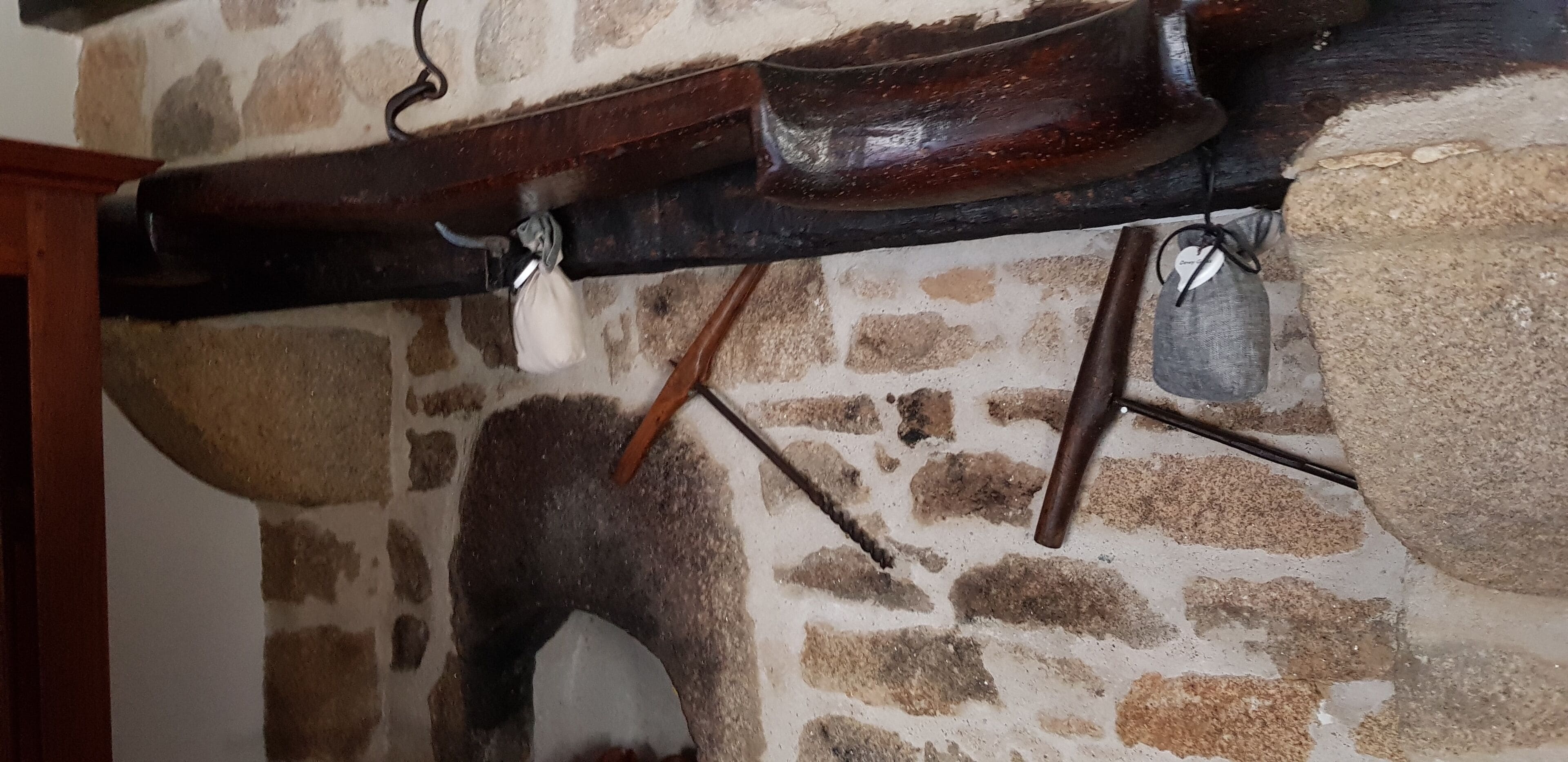 A stone wall with a wooden beam and a hanging bag.