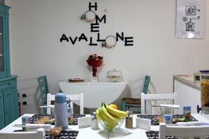 Un comedor con una mesa dispuesta para el desayuno, una decoración de pared que dice "HOME AVALONE" y un grabado de patente enmarcado.