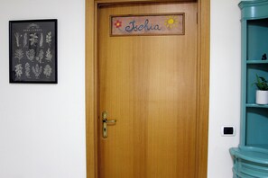 Una puerta de madera con una placa que dice "Ischia" e ilustración enmarcada de un jardín de hierbas en la pared.