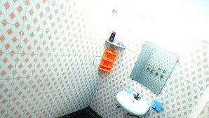 A small bathroom with a toilet, sink, and shower. - Kovo Expo Mart (Greater Noida)