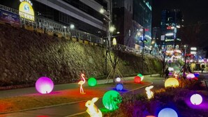 A nighttime outdoor area with illuminated sculptures of flamingos and spheres, a paved walkway, and a stone wall. - Aroma Hotel (Seoul)