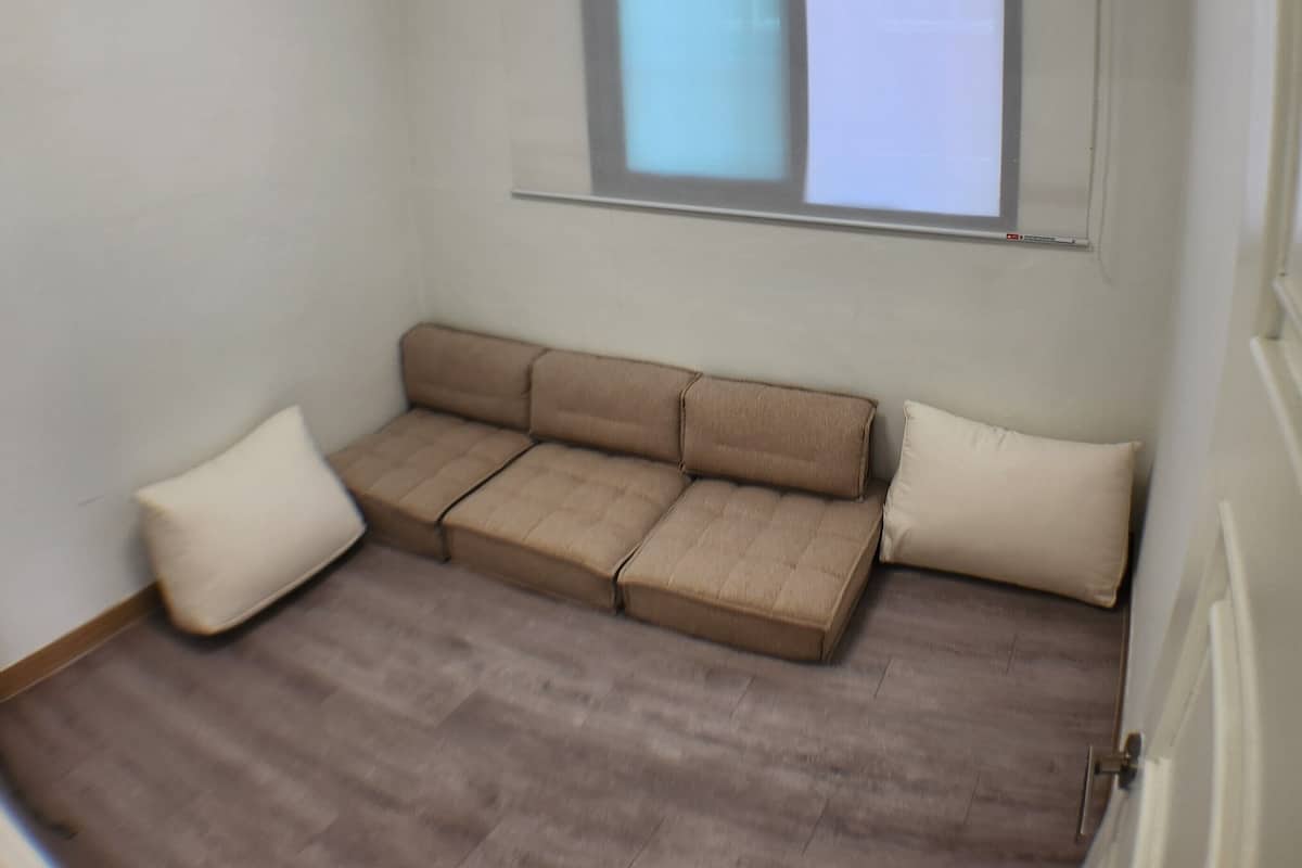 A room with a sofa, a window, and a ceiling light fixture.