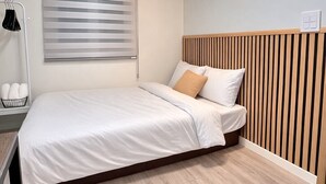 A modern bedroom with a skylight, a bed with white bedding, a wooden headboard, and a bedside lamp. - Aroma Hotel (Seoul)