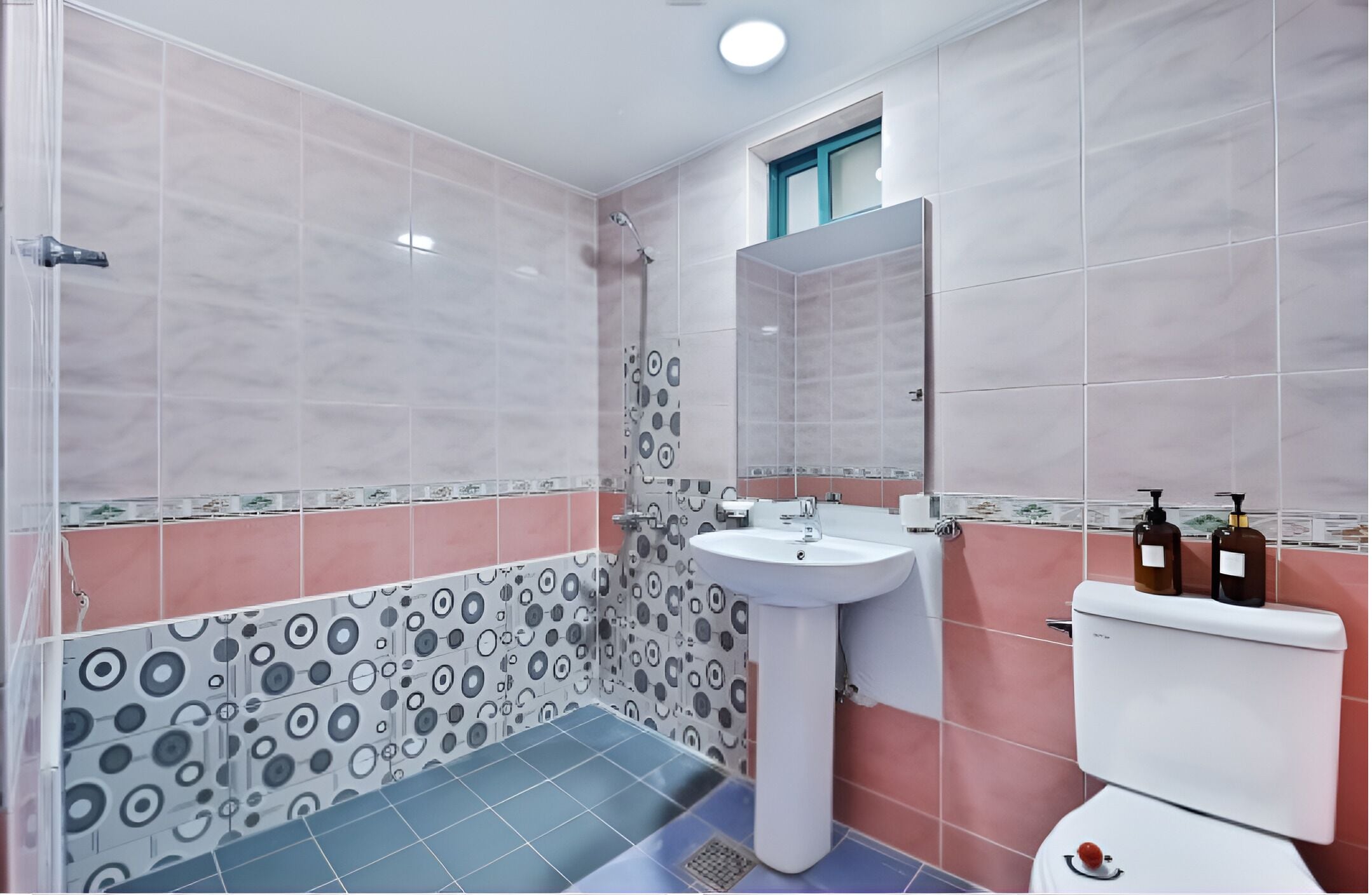 Un baño con ducha, lavamanos, inodoro y ventana.
