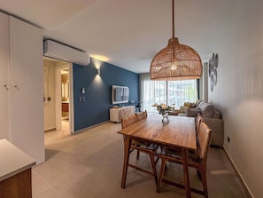 Ein modernes Wohnzimmer mit Esstisch, einer Couch und einer Pendelleuchte.