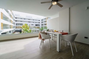Eine moderne Wohnung mit Essbereich, großen Fenstern und Deckenventilator.