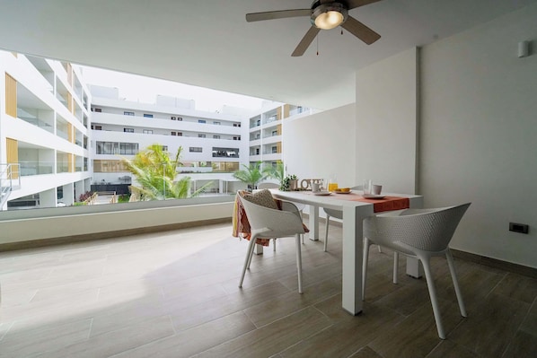 Een modern appartement met een eethoek, grote ramen en een plafondventilator.