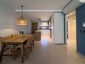 Een moderne keuken met witte kasten, een centraal eiland en een hanglamp.