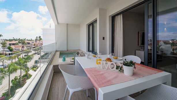 A balcony with a dining table, chairs, and a view of the cityscape. - Gorgeous new beach condo w/ PIcuzzi (Punta Cana)