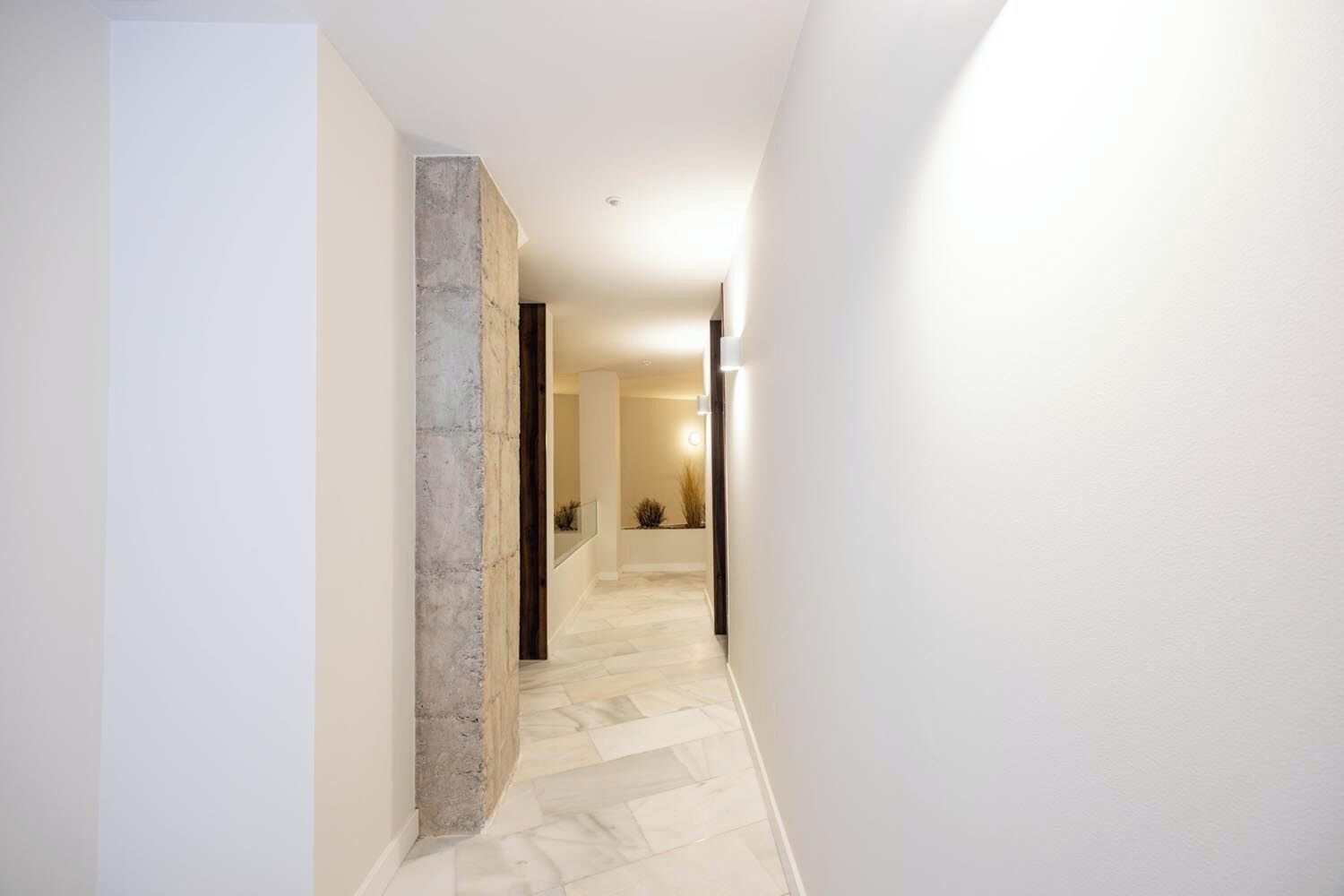 A hallway with a stone accent wall, a tiled floor, and a door leading to another room.