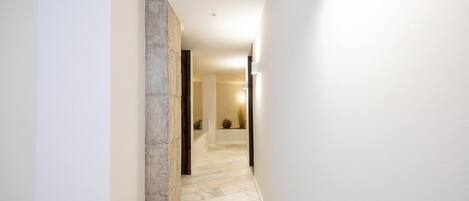 A hallway with a stone accent wall, a tiled floor, and a door leading to another room.