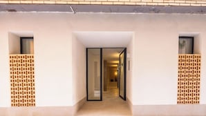 Une entrée d’immeuble avec un chemin dégagé menant à une porte vitrée.