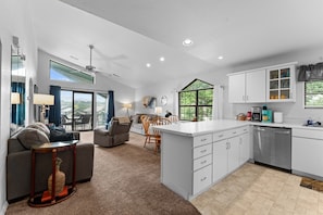 A spacious living area with a sofa, dining table, and kitchen with white cabinets and a dishwasher. - Penthouse Quiet End Unit • Near Strip + Pool (Branson)