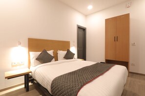 Una cama bien hecha con un edredón acolchado, cabecera de madera y dos lámparas de noche.