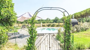 Ett avskilt poolområde med fri sikt över poolen, omgivet av grönska och en pergola.