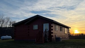 A single-story log cabin with a front porch and a small attached garage. - Charming secluded 2-bedroom cabin with WiFi, AC in peaceful Richland Center (Richland Center)