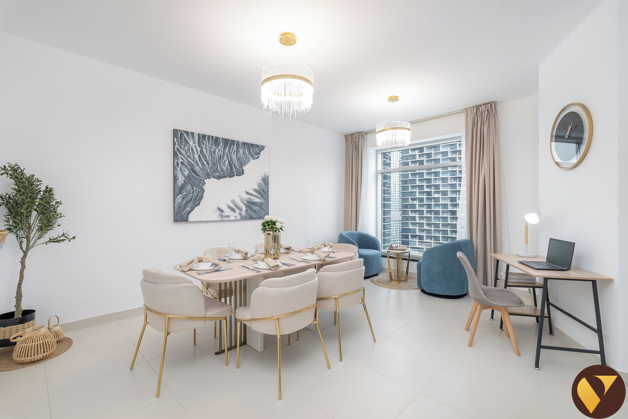 Una sala de estar moderna con comedor, un sillón azul, una computadora portátil sobre un escritorio y un amplio ventanal con vistas a la ciudad.