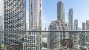 Een balkon met rieten stoelen en een kleine tafel, met uitzicht op een stadsgezicht met hoge gebouwen en een jachthaven.