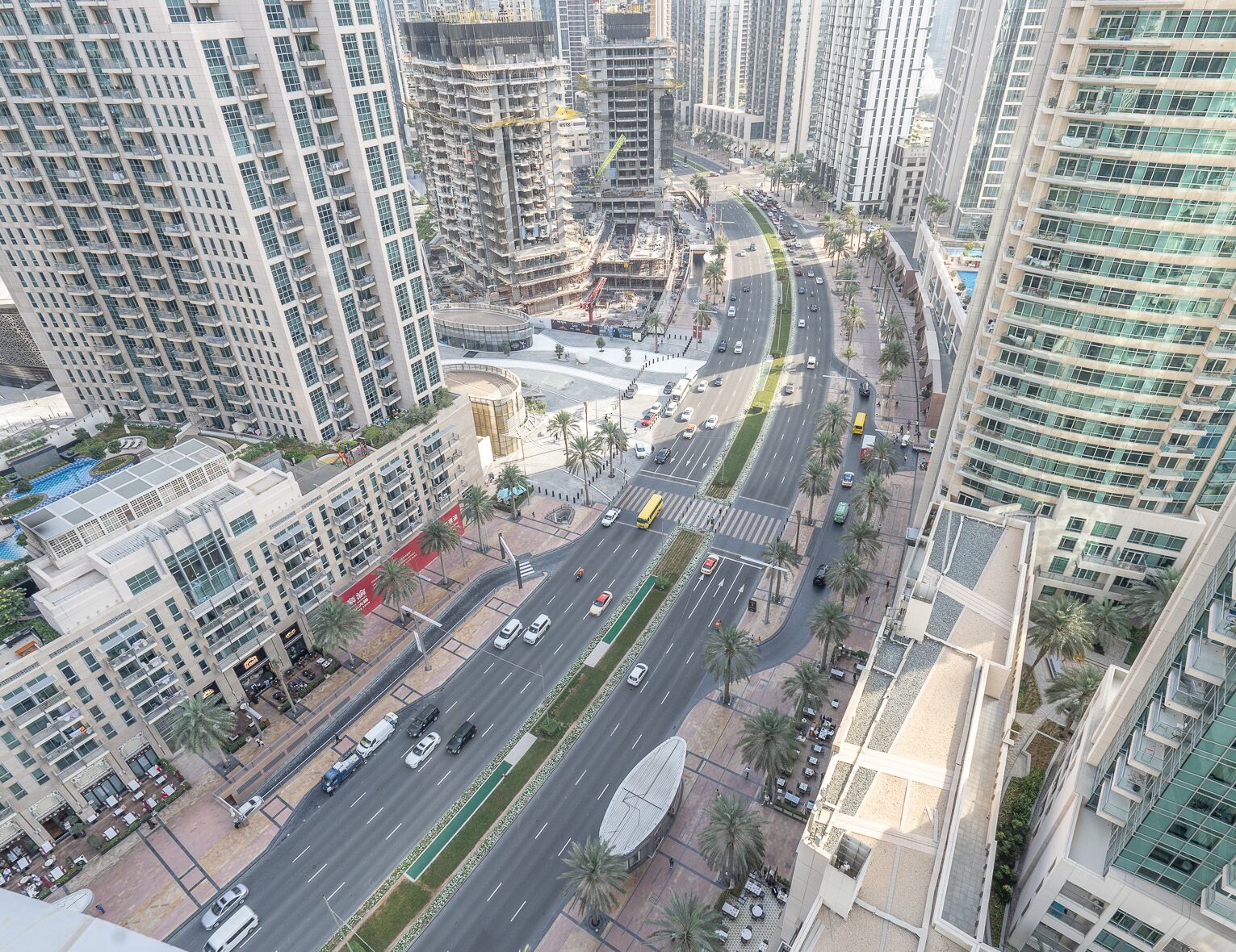 A high-rise urban area with modern buildings, a busy road, and a pedestrian walkway.