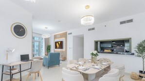 Een moderne eetruimte met een ronde tafel voor zes personen, omringd door witte stoelen met gouden poten.