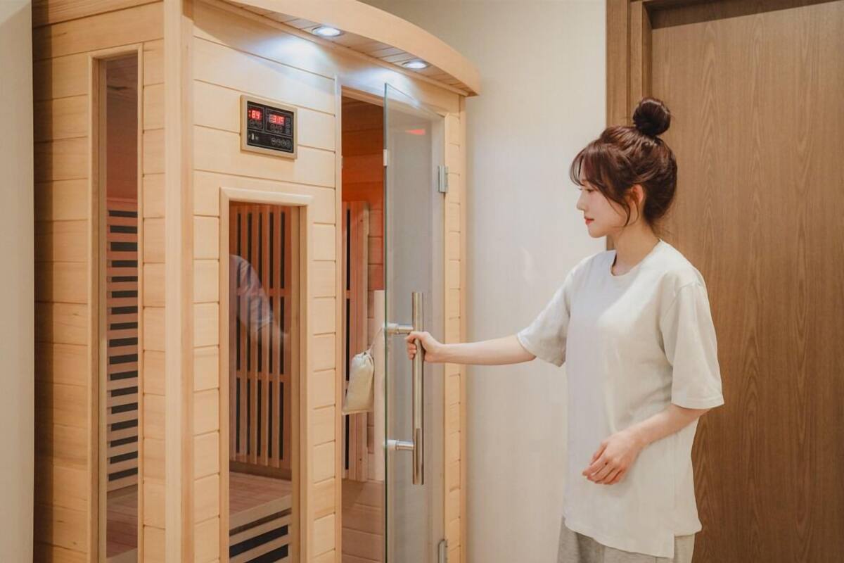 Un sauna avec une structure extérieure en bois, un écran numérique et une porte coulissante en verre.