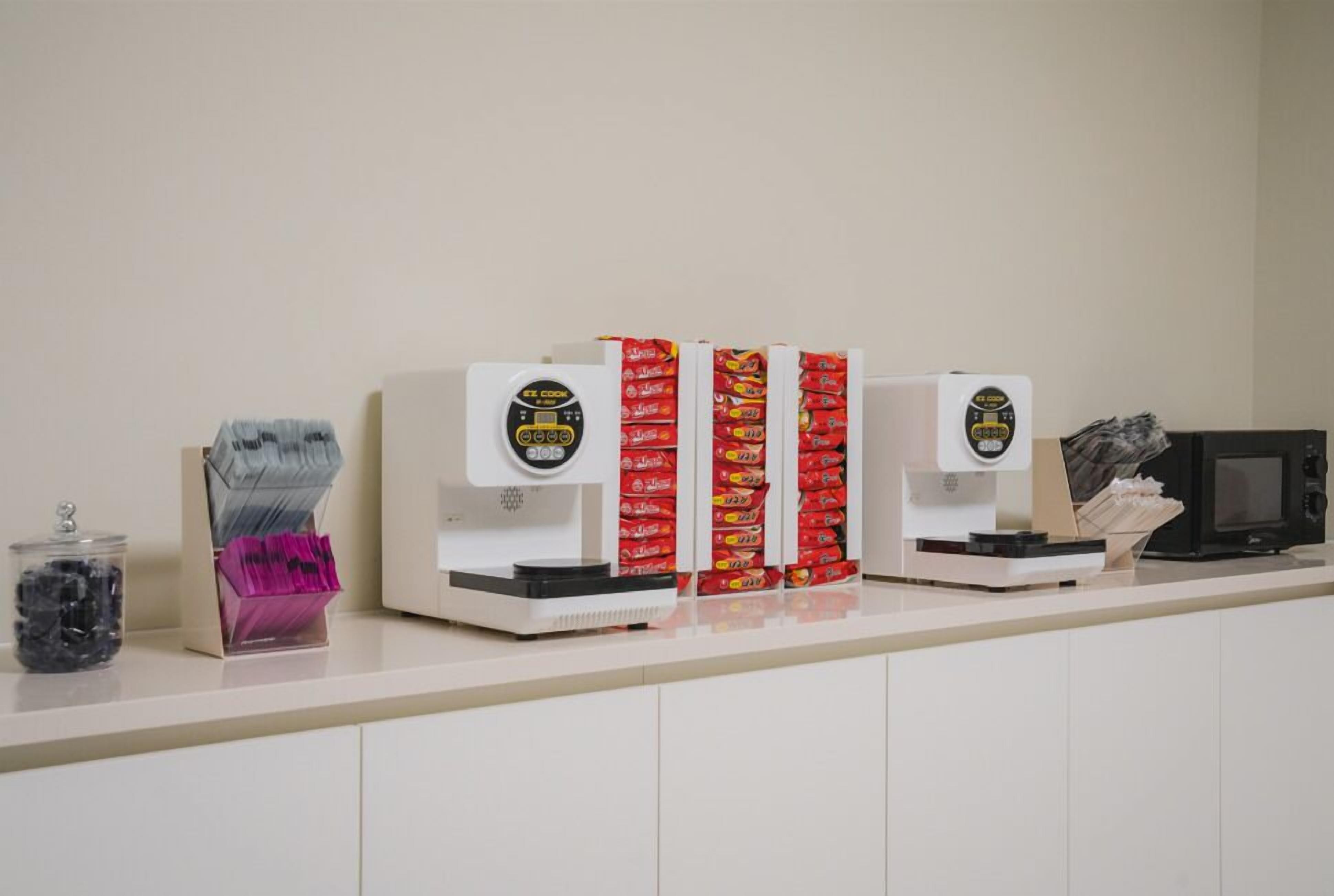 A counter with a scale, a microwave, and snack dispensers.
