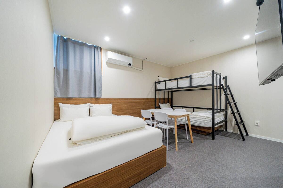Une chambre avec un lit simple, un lit superposé, un bureau et une chaise.