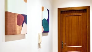 Ein Flur mit zwei abstrakten Bildern an der Wand und einer Holztür.