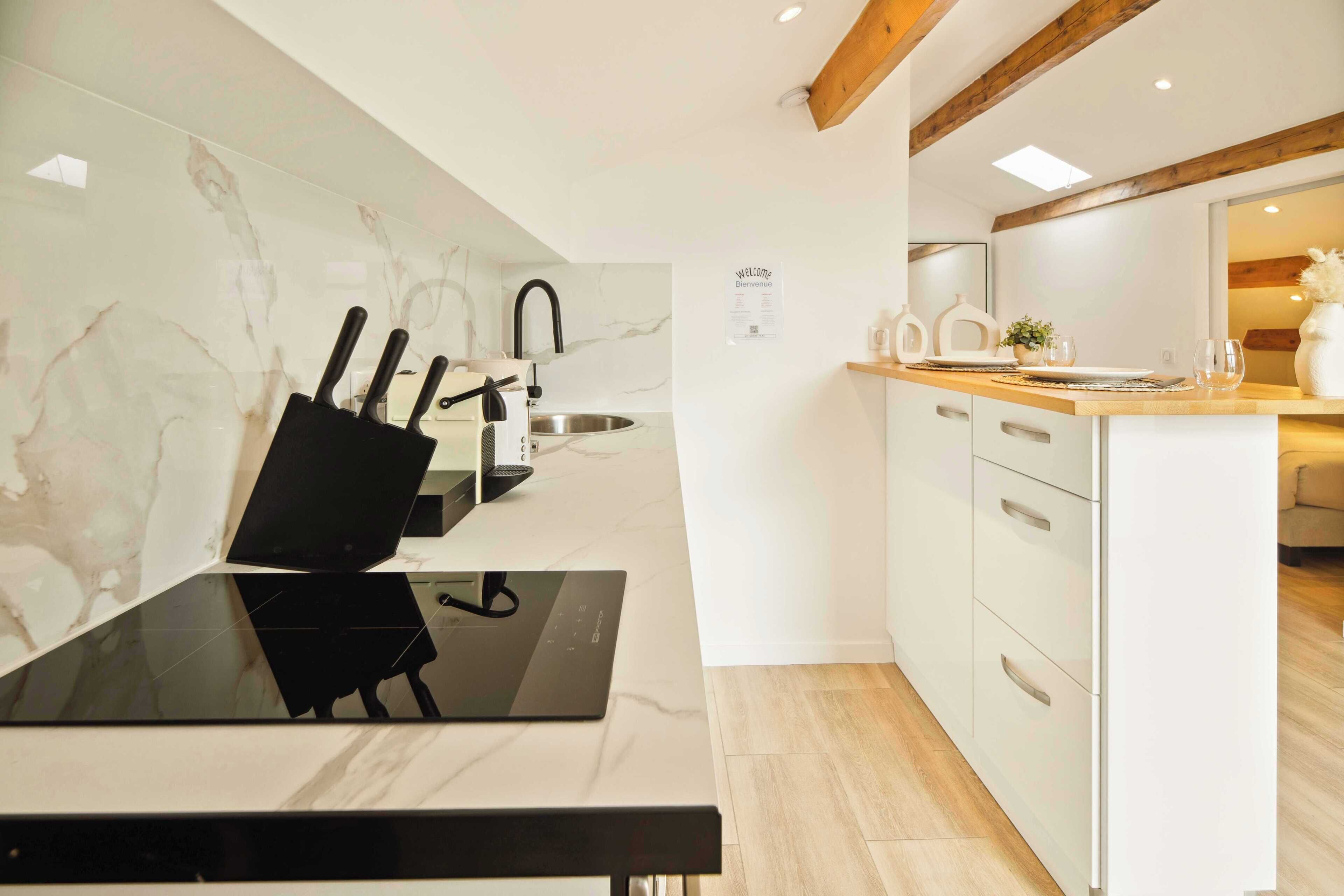 A modern kitchen with a black countertop, white cabinets, and a marble backsplash.