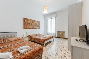 Ein Hotelzimmer mit zwei Betten, einem Gemälde, einem Heizkörper und einem Fernseher.