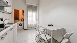 Una cocina compacta con lavadora, lavamanos y una mesa con sillas.
