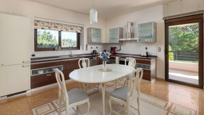 Una cocina moderna con una mesa de comedor redonda, sillas blancas y un florero con flores.