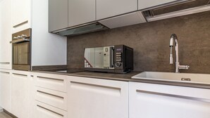 A modern kitchen with a built-in microwave, a stainless steel faucet, and white cabinetry.
