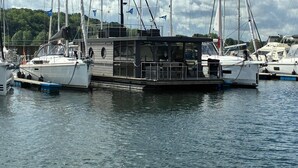 Un port de plaisance où sont amarrés plusieurs voiliers, doté d’une terrasse couverte et d’un espace de pont ouvert.
