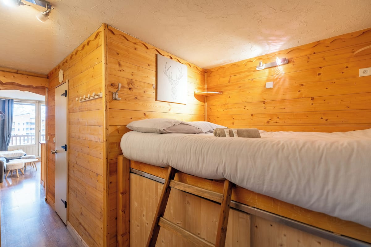 A wooden cabin room with a bunk bed, a small table, and a chair.