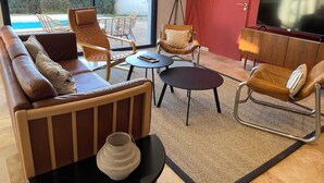 Een moderne woonkamer met een bank, twee fauteuils, een salontafel en een televisie.