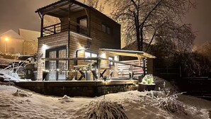 Uma cabana de madeira com varanda, rodeada por neve.
