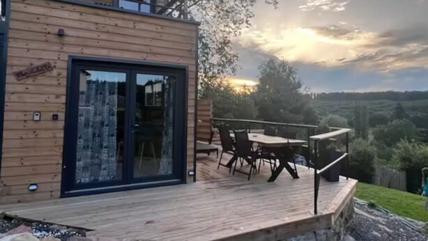 Um deck de madeira com porta de vidro, móveis de exterior e vista panorâmica.