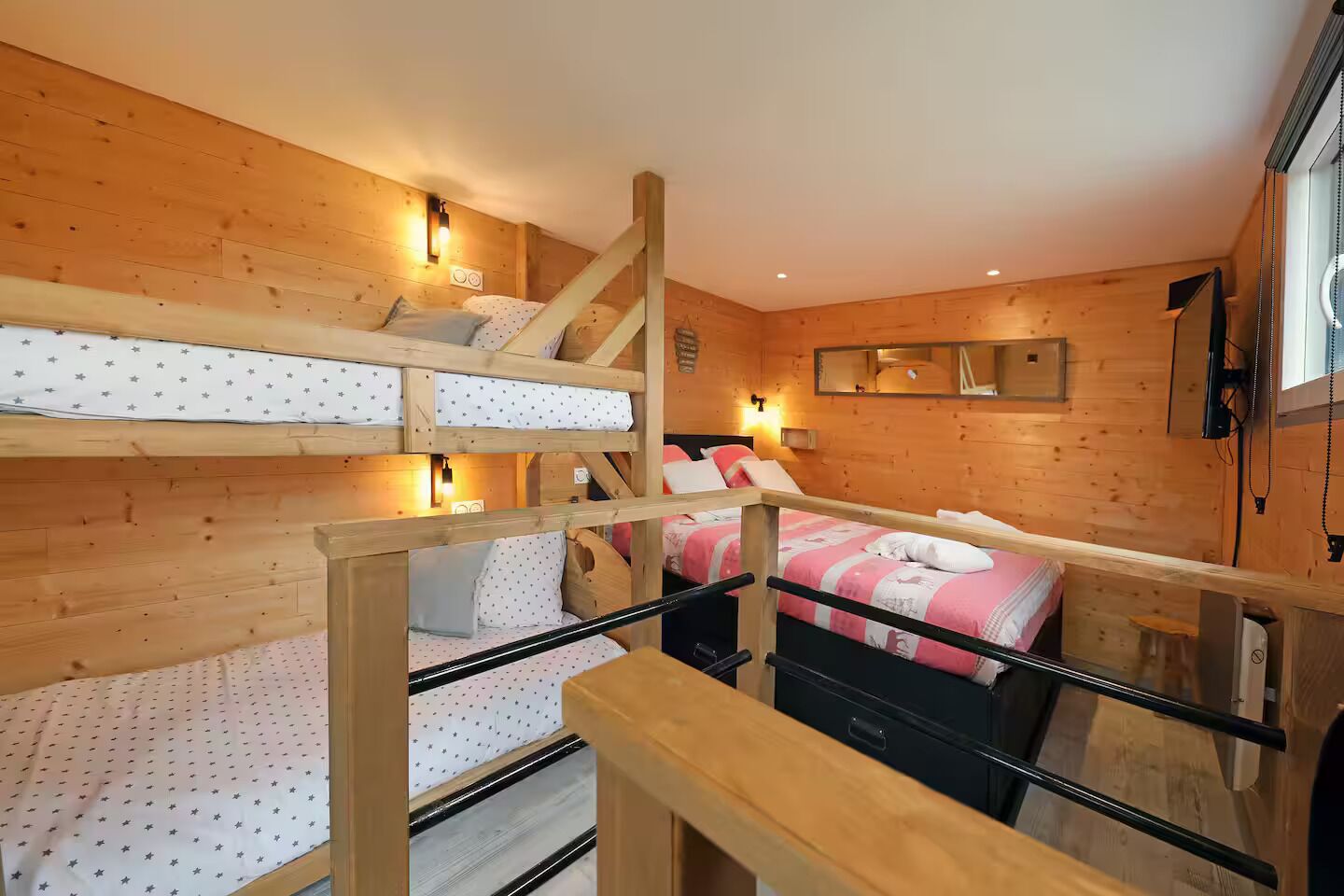 Habitación con literas, paredes de madera, escalera y espejo.