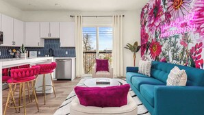 A modern living room with a teal sofa, a coffee table, and vibrant floral wallpaper. - The WildFlower condo in Music City near downtown (Nashville)