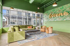 Un espace détente avec des canapés verts, un tapis à motifs et un mur sur lequel le mot « Dolene » est écrit en grandes lettres.