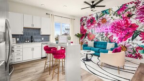 A modern kitchen with white cabinets, a built-in oven, and a bar area with pink bar stools. - The WildFlower condo in Music City near downtown (Nashville)