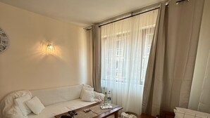 Una stanza accogliente con un divano, un letto, un tavolino in legno e una lampada a parete.