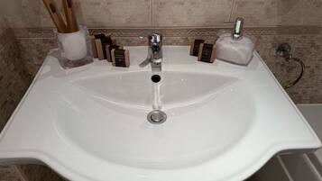 Un lavamanos de baño con un grifo moderno, dispensadores de jabón y porta cepillos de dientes.